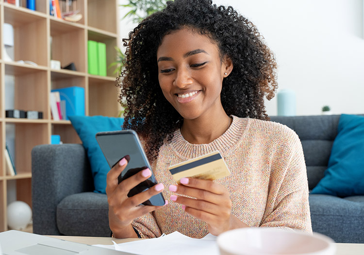 Smiling woman paying with card by phone